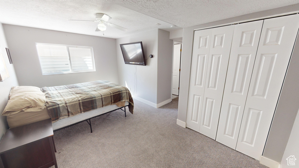 Bedroom with a closet, light carpet, a textured ceiling, and ceiling fan