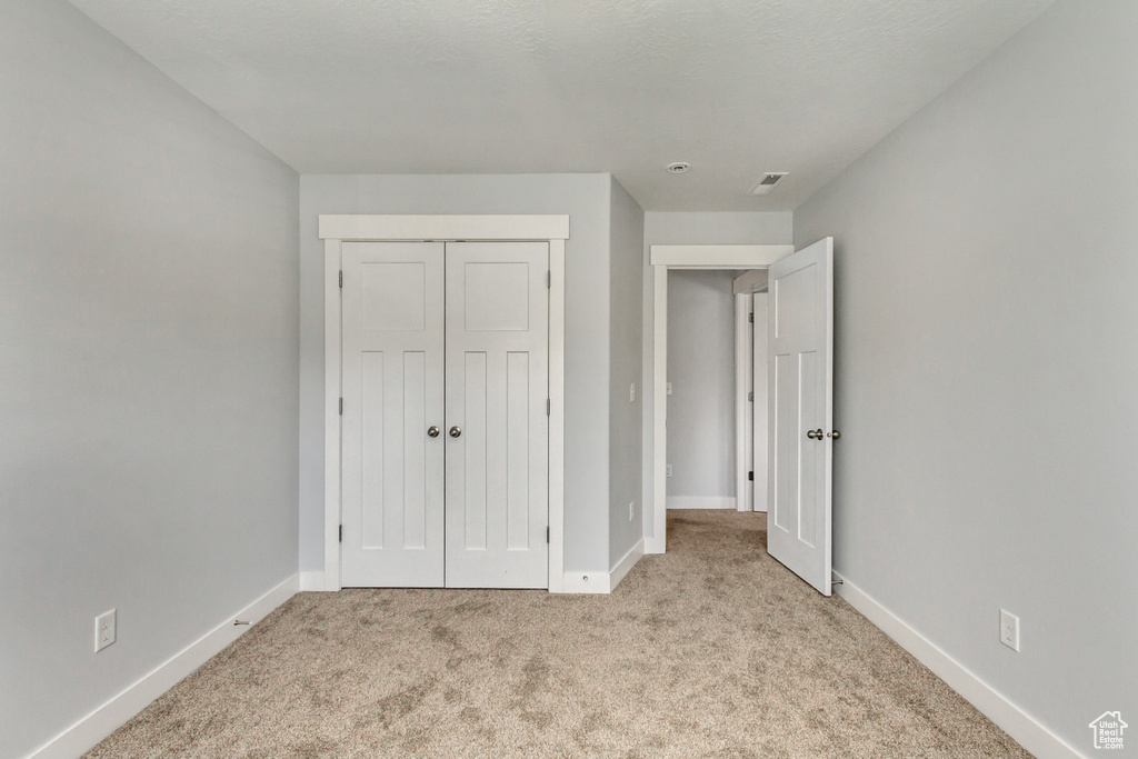 Unfurnished bedroom with a closet and light colored carpet