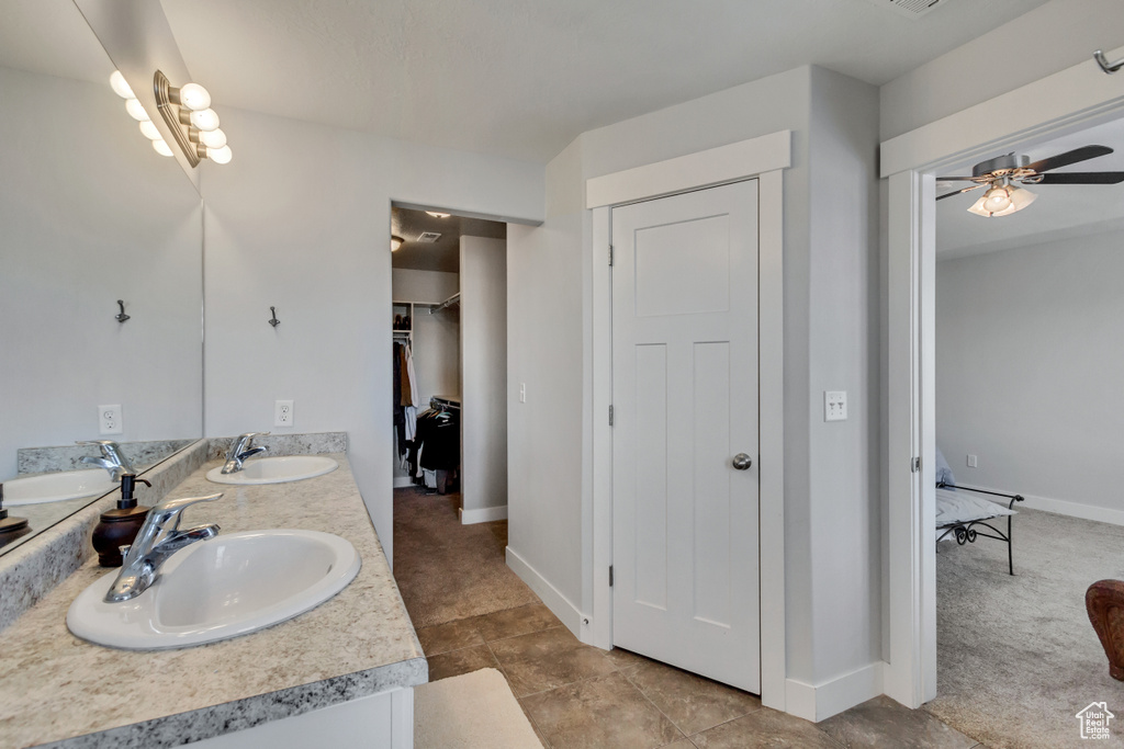 Bathroom featuring vanity with extensive cabinet space, tile flooring, dual sinks, and ceiling fan