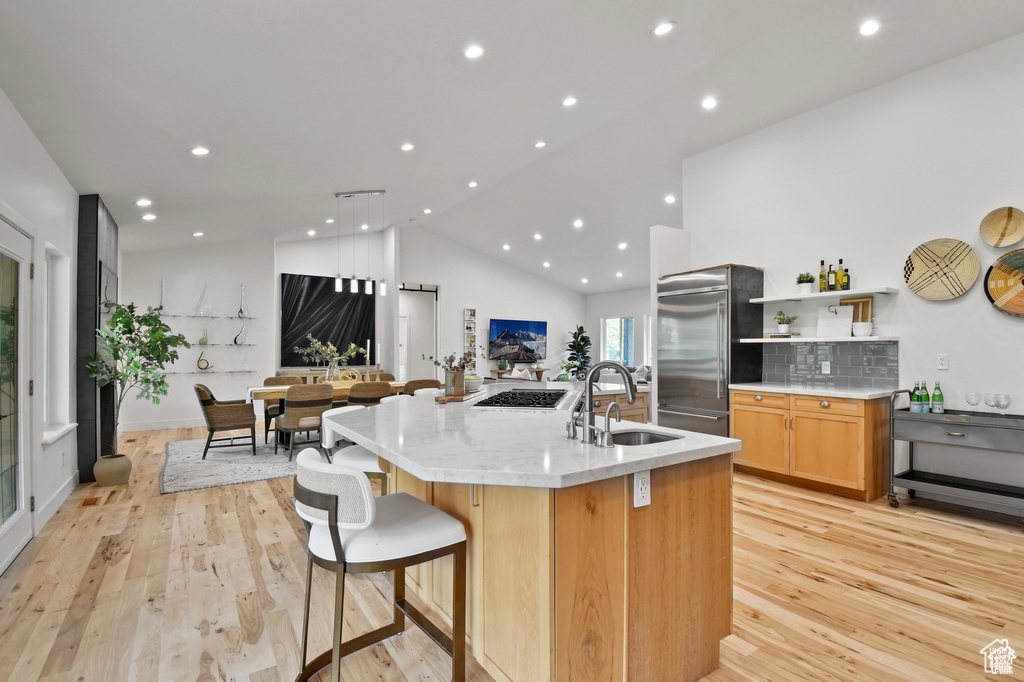 Kitchen featuring appliances with stainless steel finishes, an island with sink, sink, and light hardwood / wood-style flooring