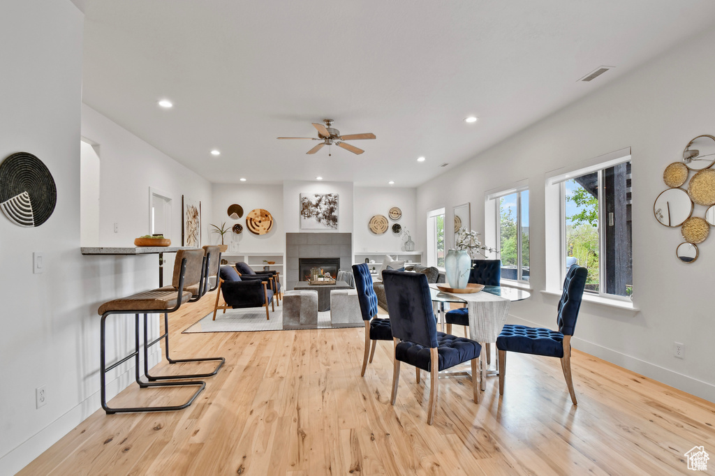 Dining space featuring light hardwood / wood-style floors, ceiling fan, and a tile fireplace