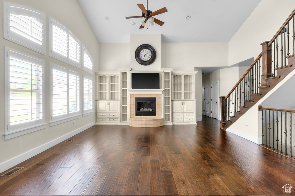 Unfurnished living room with high vaulted ceiling, dark hardwood / wood-style flooring, a fireplace, and ceiling fan