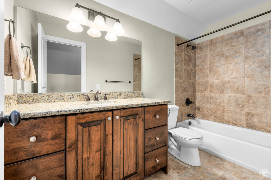 Full bathroom with tiled shower / bath combo, vanity, tile floors, and toilet
