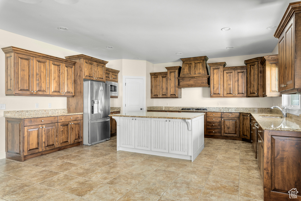 Kitchen with stainless steel appliances, a center island, light tile flooring, a kitchen bar, and custom range hood