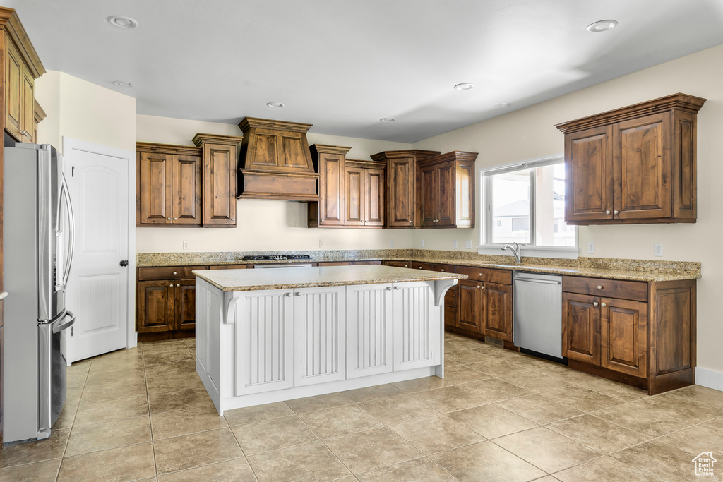 Kitchen with a center island, stainless steel appliances, light tile flooring, and premium range hood