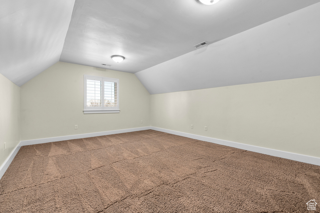 Additional living space featuring light carpet and lofted ceiling