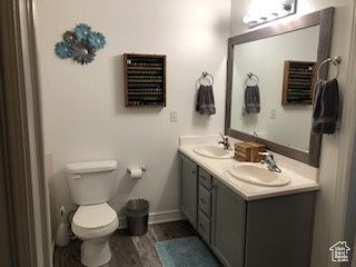 Bathroom with hardwood / wood-style floors, toilet, and double sink vanity