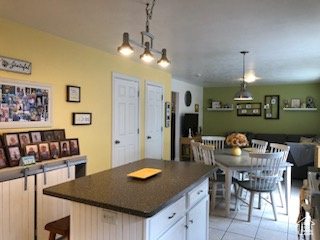 Kitchen with decorative light fixtures, white cabinetry, light tile floors, and a center island