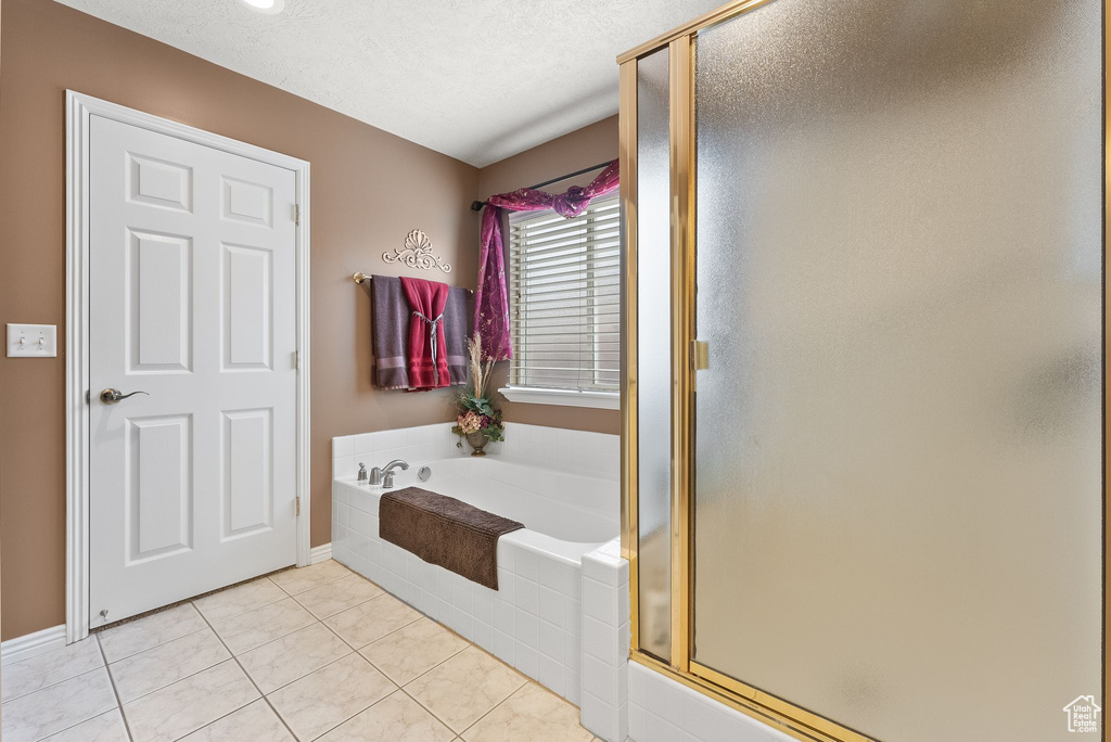 Bathroom with plus walk in shower, tile floors, and a textured ceiling