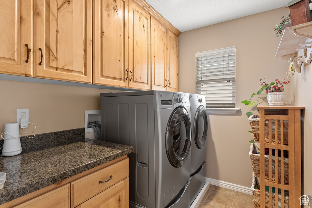 Laundry area with hookup for a washing machine, cabinets, independent washer and dryer, and light tile floors