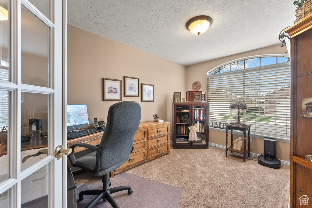 Carpeted office space with french doors and a textured ceiling