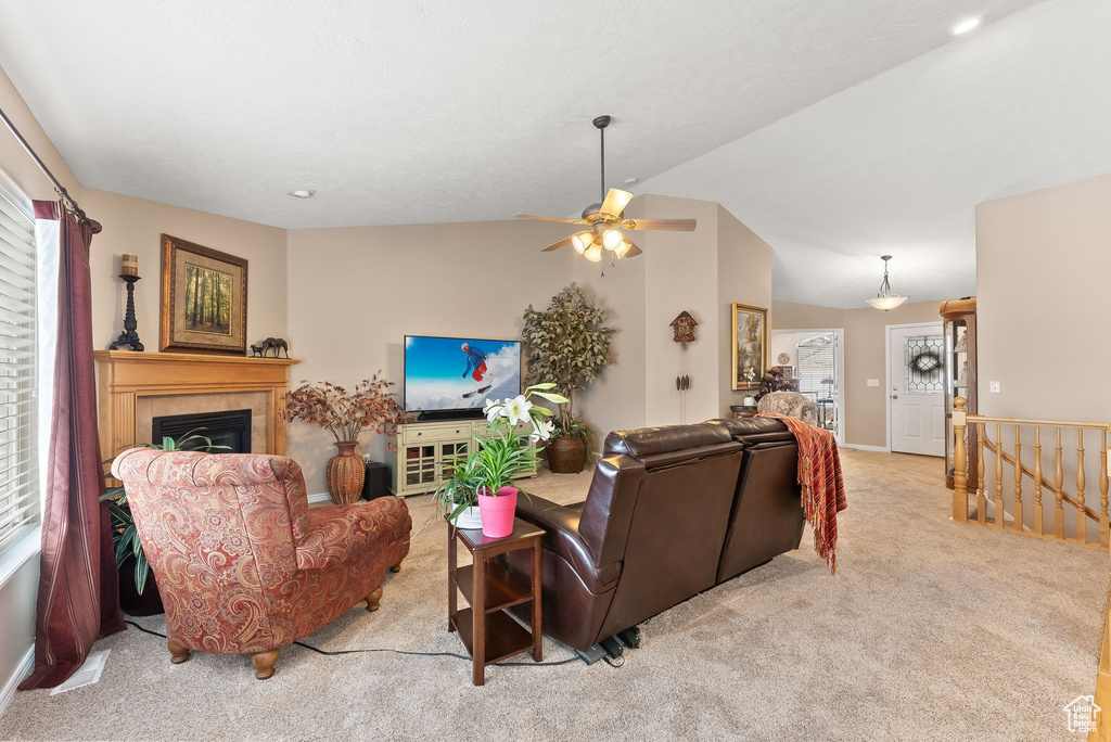 Living room with ceiling fan, vaulted ceiling, and light colored carpet