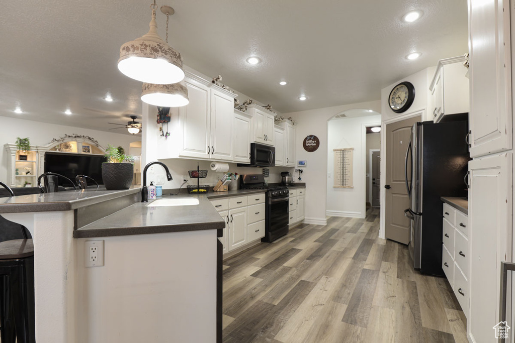 Kitchen featuring pendant lighting, ceiling fan, kitchen peninsula, black appliances, and sink