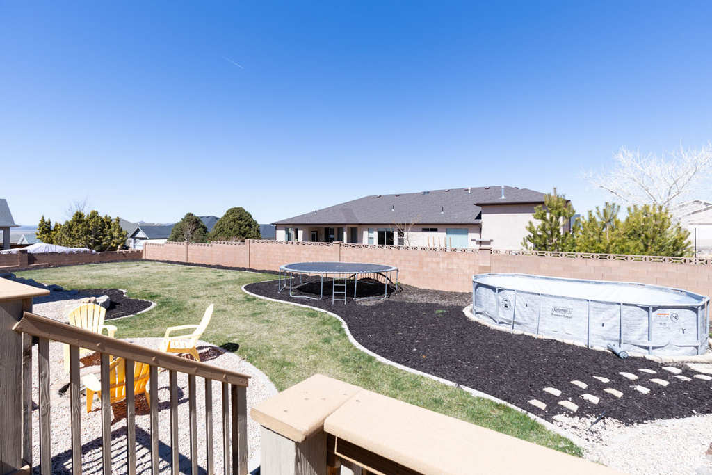 View of yard featuring a fenced in pool and a trampoline
