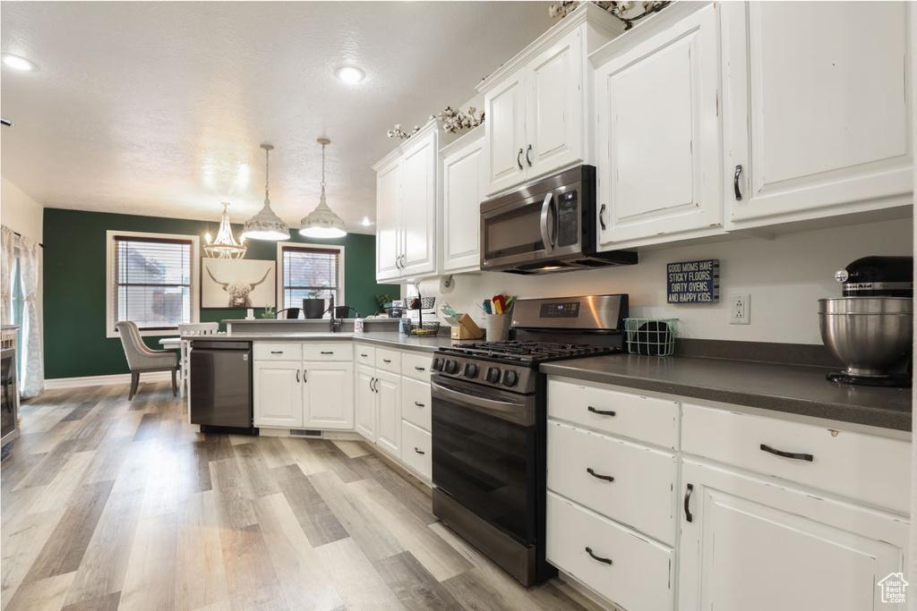 Kitchen with white cabinetry, gas range oven, dishwasher, and light wood-type flooring
