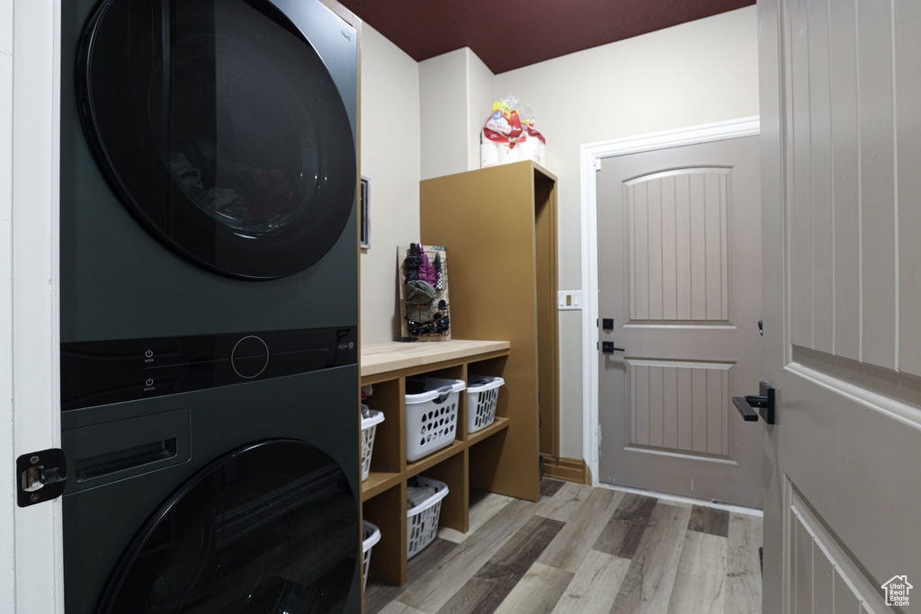 Laundry area featuring light hardwood / wood-style floors and stacked washer and dryer