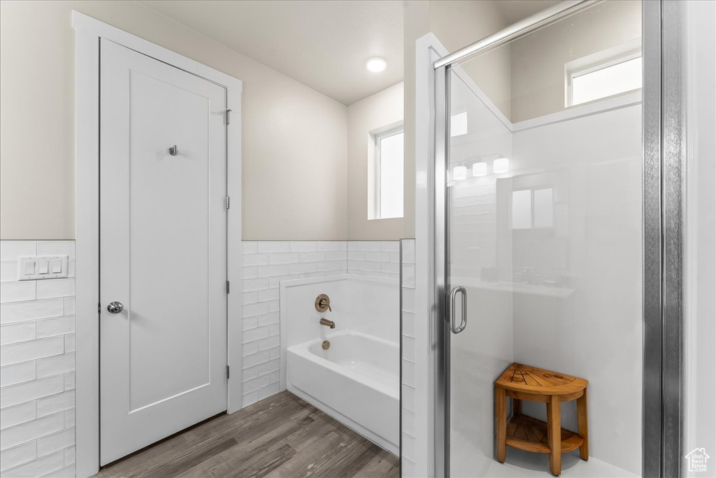 Bathroom with tile walls, separate shower and tub, and wood-type flooring