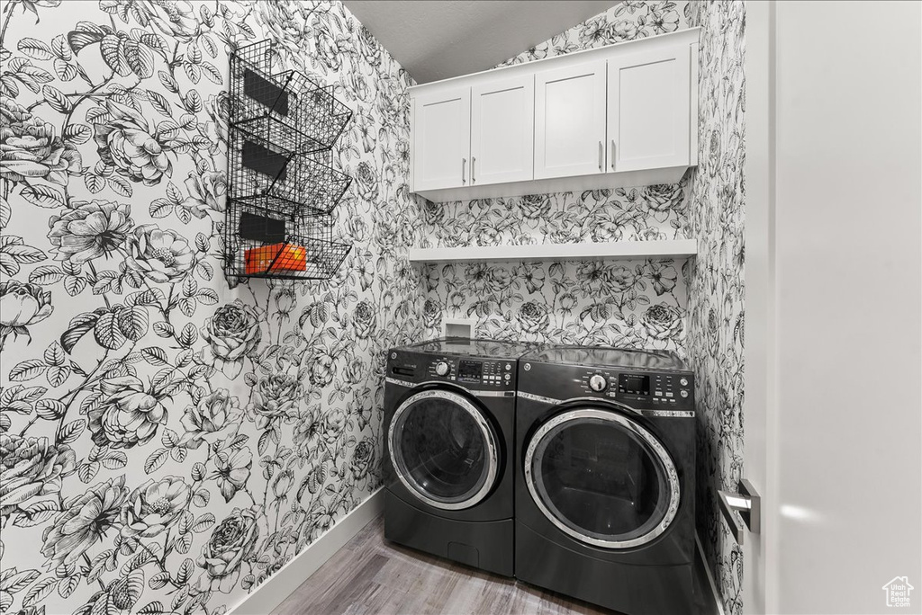 Laundry area with washing machine and clothes dryer, washer hookup, cabinets, and light wood-type flooring
