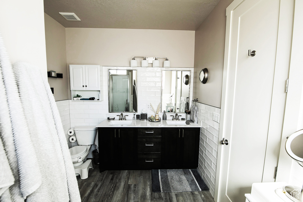 Bathroom featuring toilet, double vanity, wood-type flooring, and tile walls