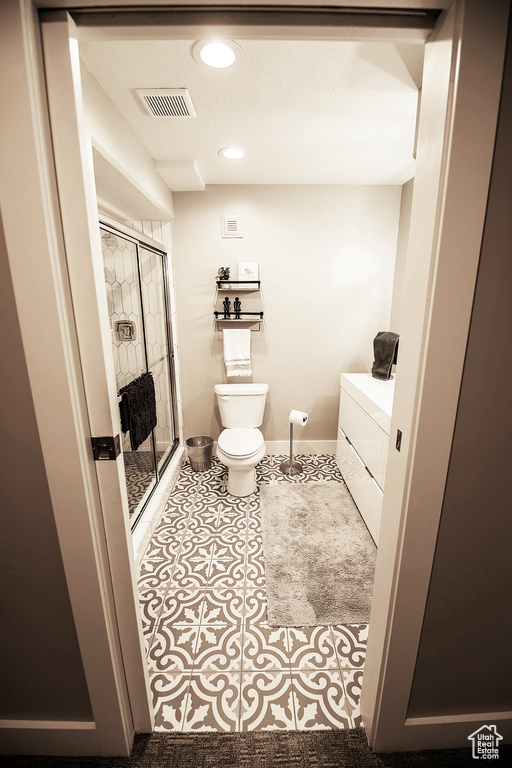 Bathroom featuring washer / clothes dryer, toilet, a shower with shower door, and tile flooring