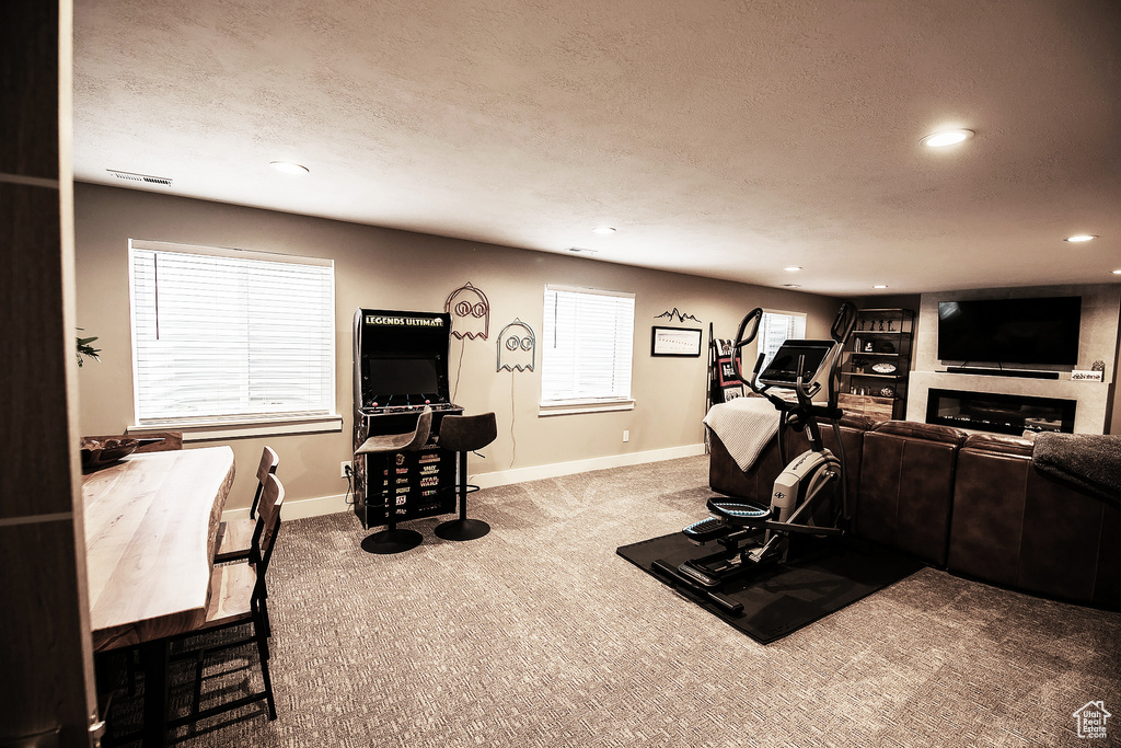Exercise room with a large fireplace, a textured ceiling, and light colored carpet