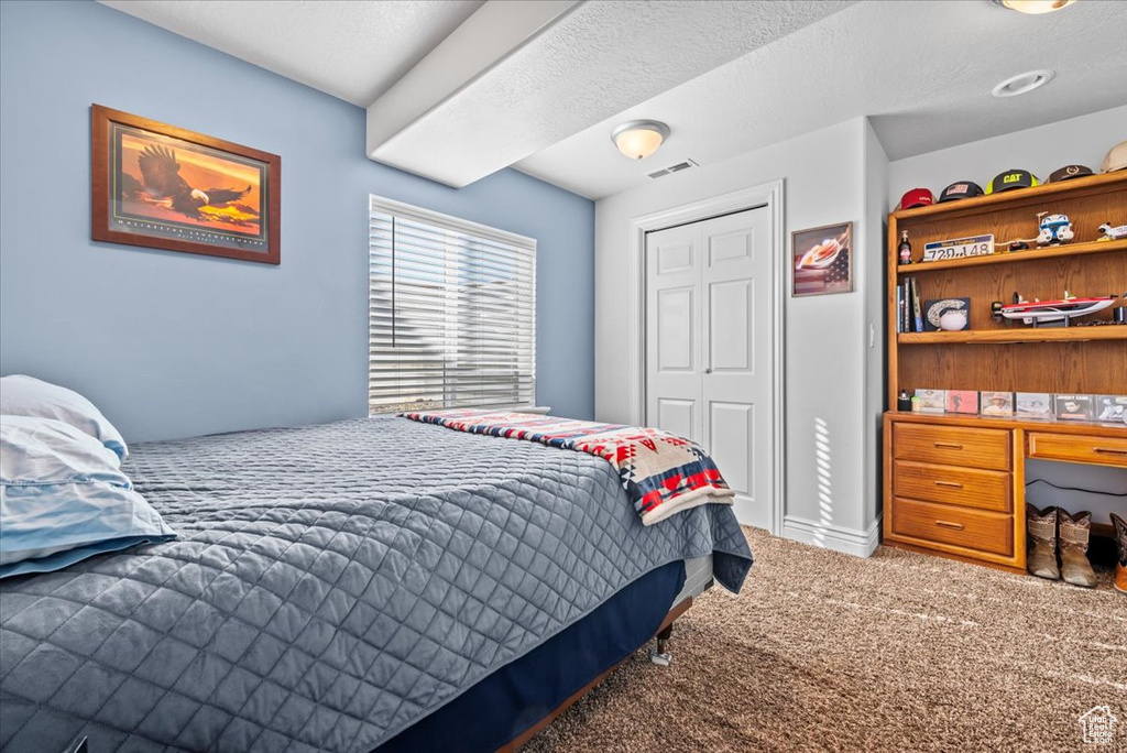 Bedroom with a textured ceiling, a closet, and carpet