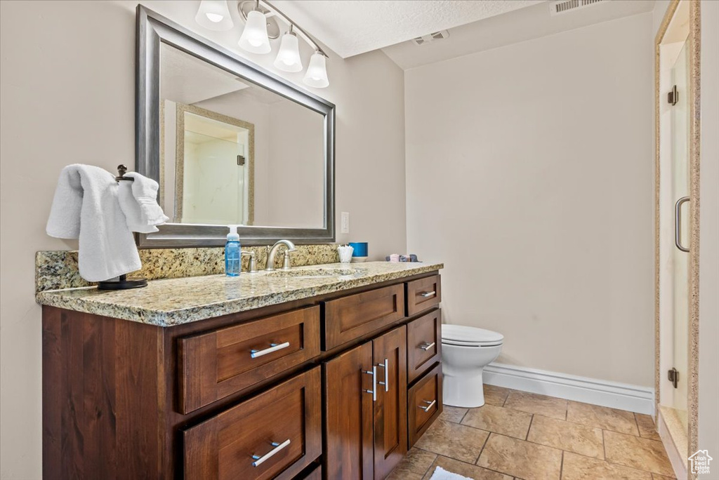 Bathroom featuring toilet, a textured ceiling, vanity, and tile flooring