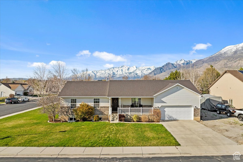 Ranch-style house with a front yard, covered porch, a mountain view, and a garage