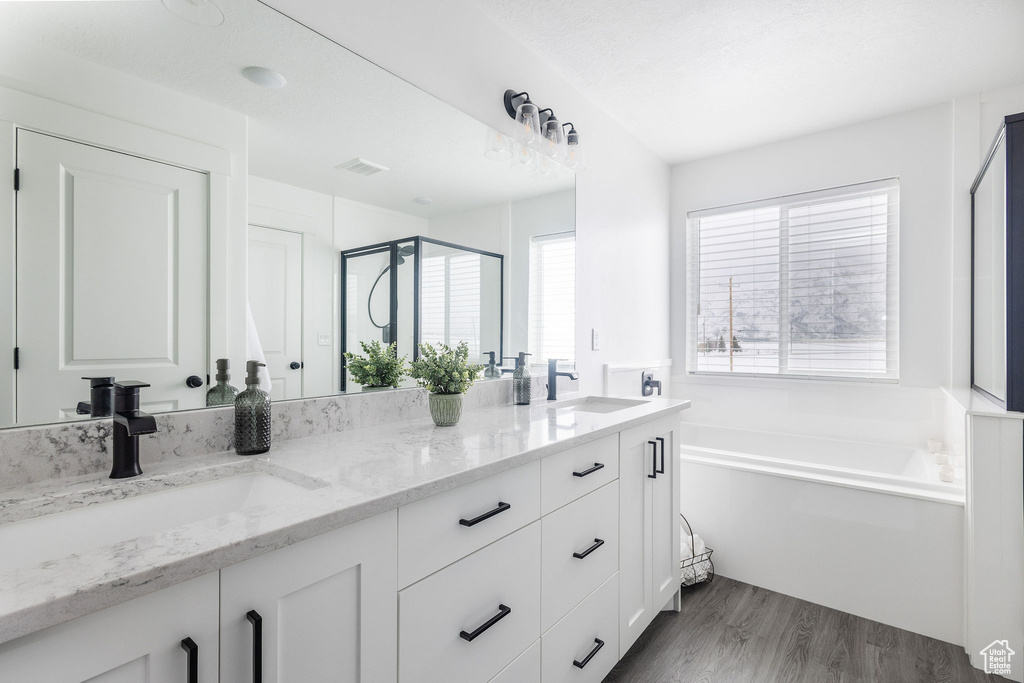 Bathroom featuring double vanity, hardwood / wood-style flooring, and separate shower and tub