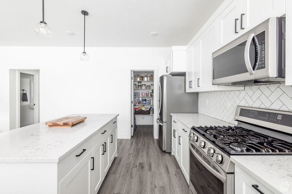 Kitchen featuring light hardwood / wood-style floors, tasteful backsplash, light stone counters, and stainless steel appliances
