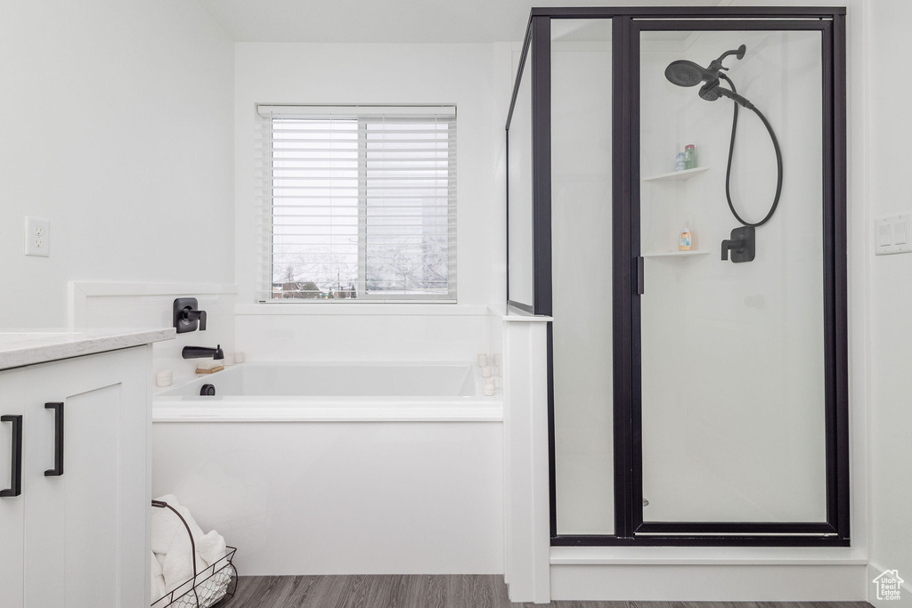 Bathroom featuring shower with separate bathtub, vanity, and hardwood / wood-style floors