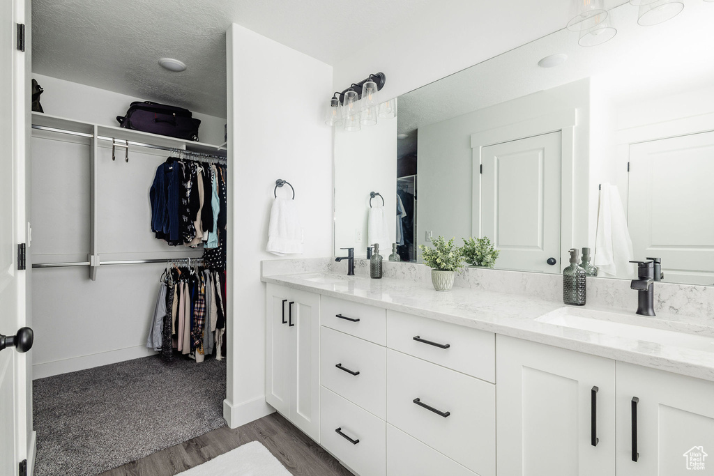 Bathroom with hardwood / wood-style floors, dual sinks, and vanity with extensive cabinet space