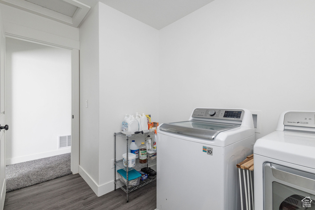 Laundry room with dark wood-type flooring and washing machine and clothes dryer