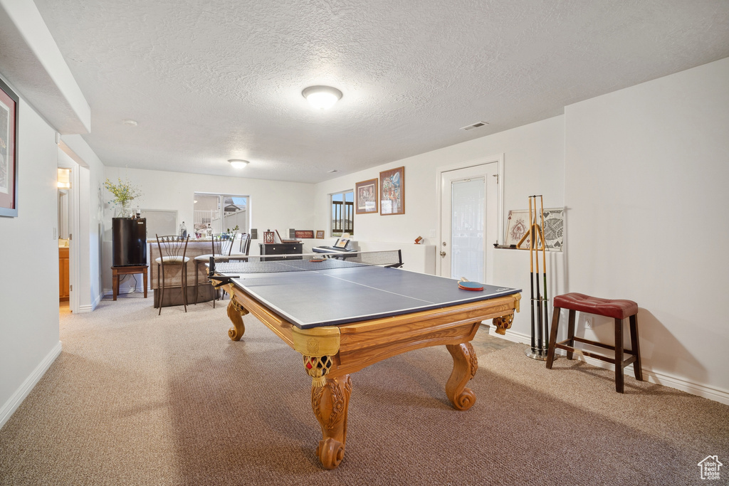 Recreation room featuring light colored carpet, pool table, and a textured ceiling