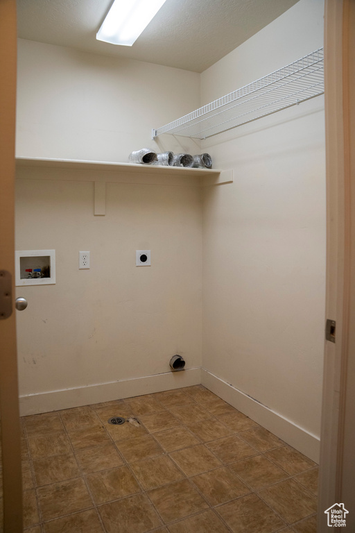 Clothes washing area with electric dryer hookup, washer hookup, and dark tile flooring