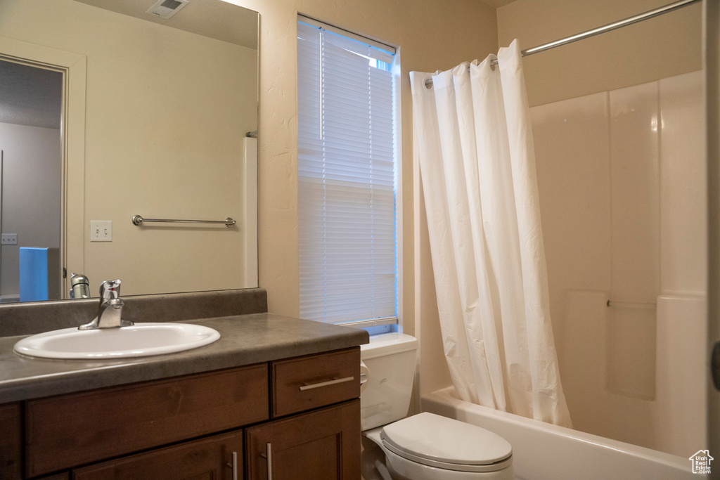 Full bathroom featuring toilet, shower / tub combo with curtain, and vanity with extensive cabinet space