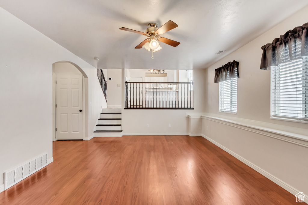 Spare room featuring ceiling fan with notable chandelier and light hardwood / wood-style flooring