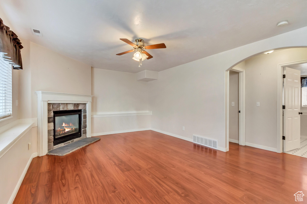 Unfurnished living room featuring light hardwood / wood-style floors, ceiling fan, and a tiled fireplace