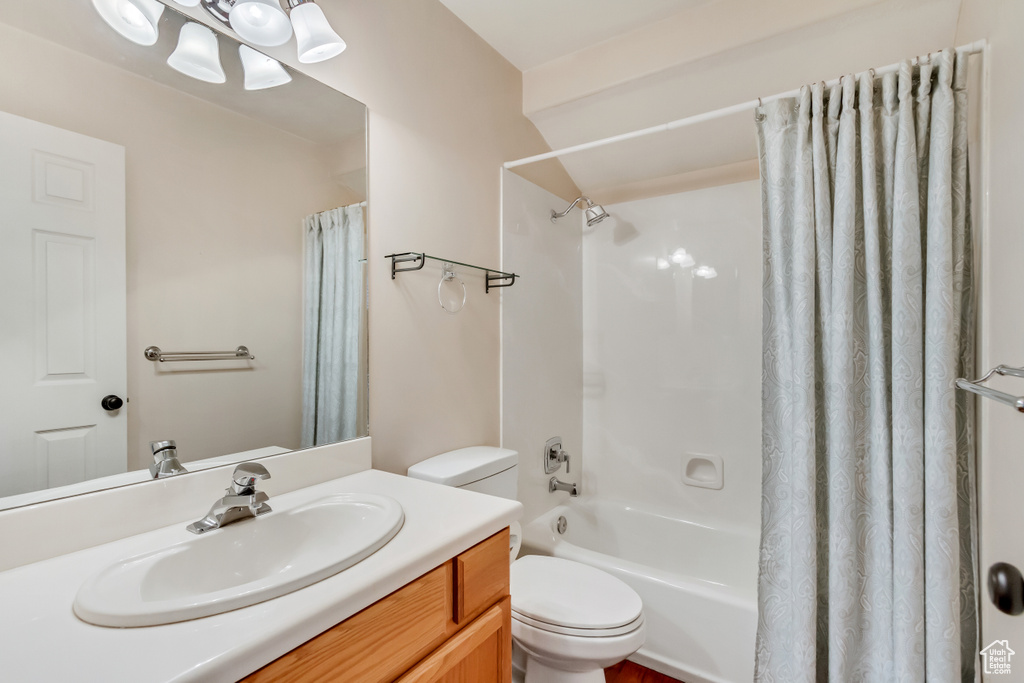 Full bathroom with vanity, shower / bath combo with shower curtain, and toilet
