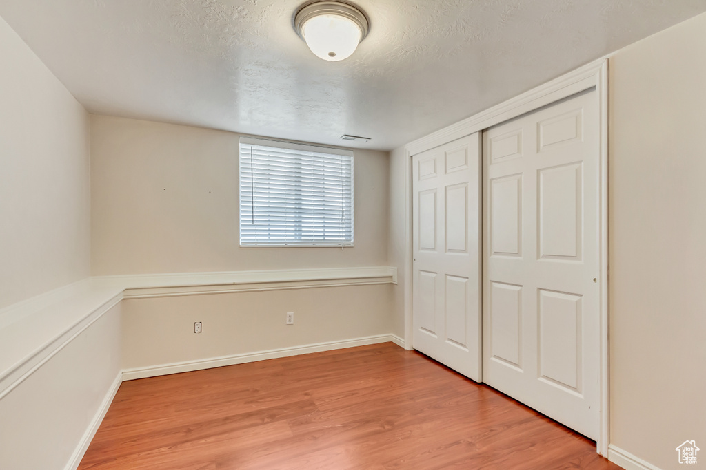 Unfurnished bedroom featuring a closet, a textured ceiling, and light hardwood / wood-style flooring
