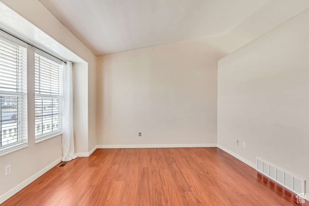 Unfurnished room with vaulted ceiling, a healthy amount of sunlight, and light hardwood / wood-style flooring