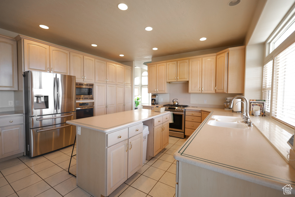 Kitchen with sink, stainless steel appliances, light tile floors, a center island, and a breakfast bar area