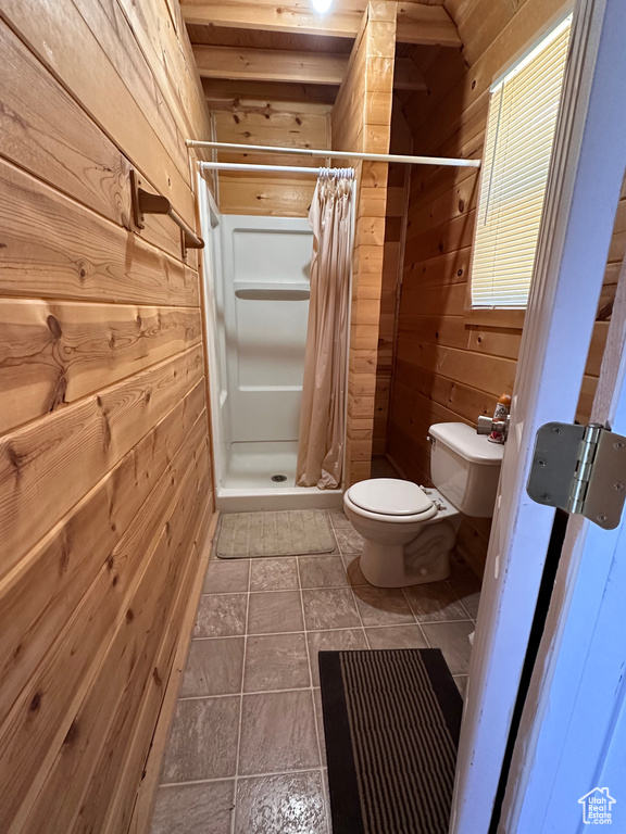 Bathroom featuring wood walls, tile flooring, a shower with curtain, and toilet