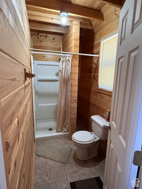 Bathroom featuring walk in shower, tile floors, toilet, and wooden walls