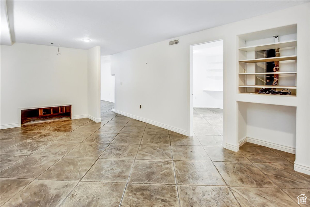 Unfurnished living room with tile flooring and built in shelves