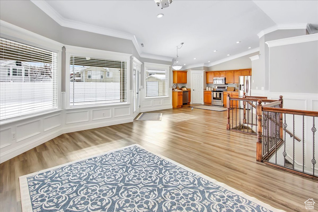 Interior space with a wealth of natural light, vaulted ceiling, light wood-type flooring, and crown molding