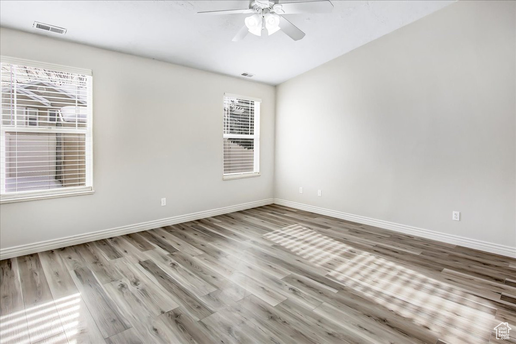 Unfurnished room featuring a healthy amount of sunlight, ceiling fan, and light wood-type flooring