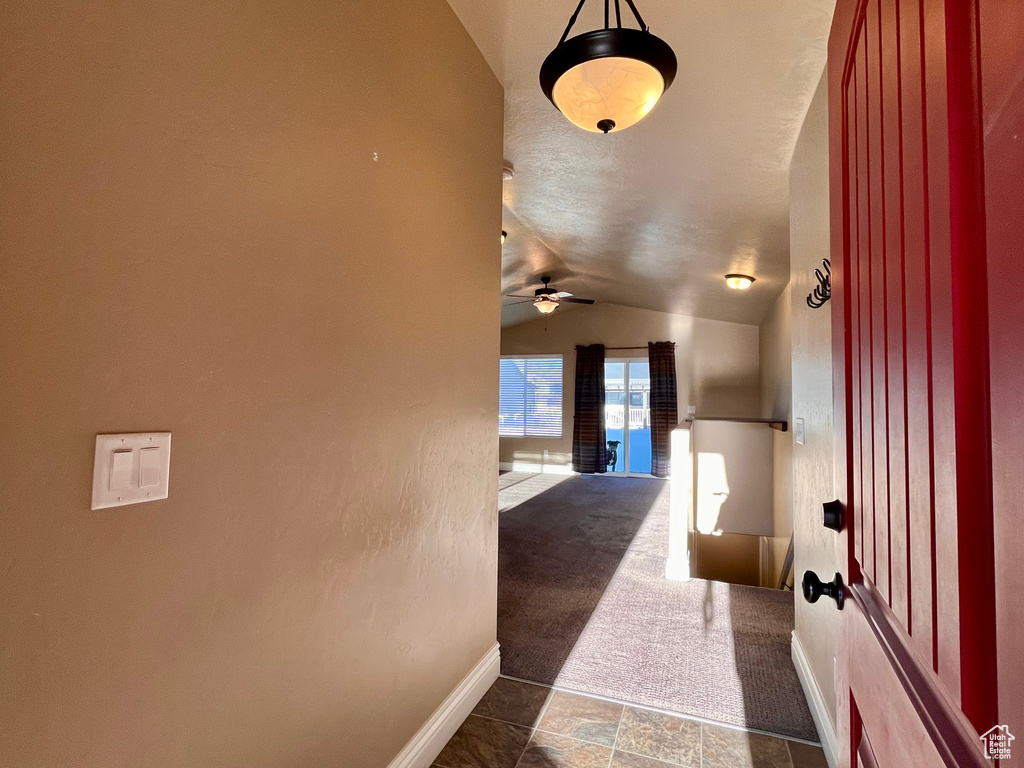 Hallway featuring dark colored carpet and vaulted ceiling