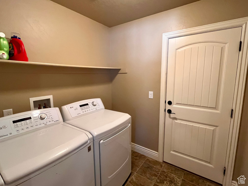 Clothes washing area featuring hookup for a washing machine, dark tile floors, and washing machine and clothes dryer