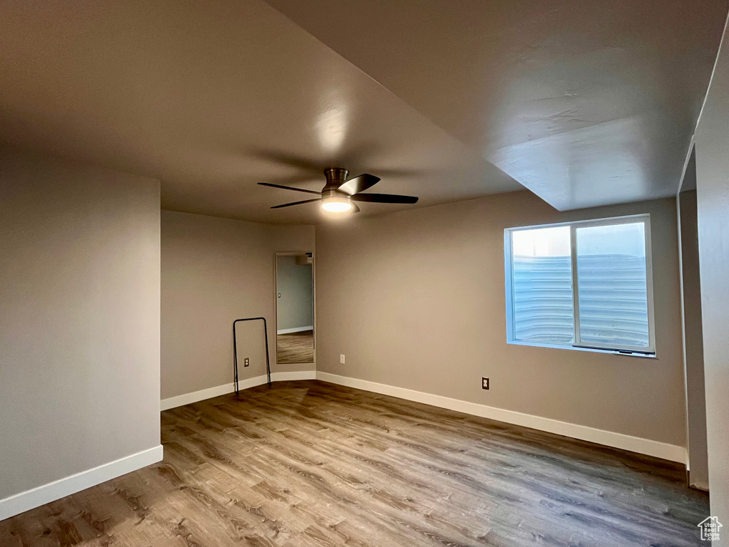 Empty room with ceiling fan and hardwood / wood-style flooring